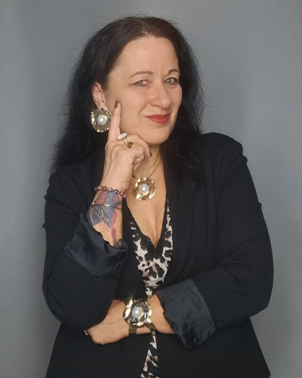 Sandra mit schwarzem Blazer und Hand am Gesicht